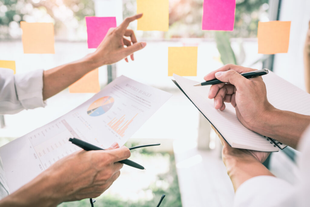 Business people meeting at office and use sticky notes on glass wall in office, diverse employees people group planning work together brainstorm strategy